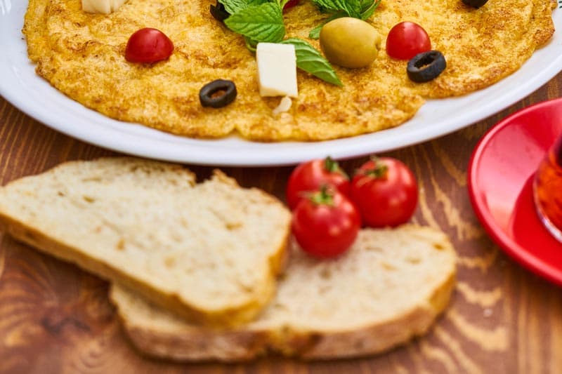 pão integral, tomates e um prato com comida mediterrânea